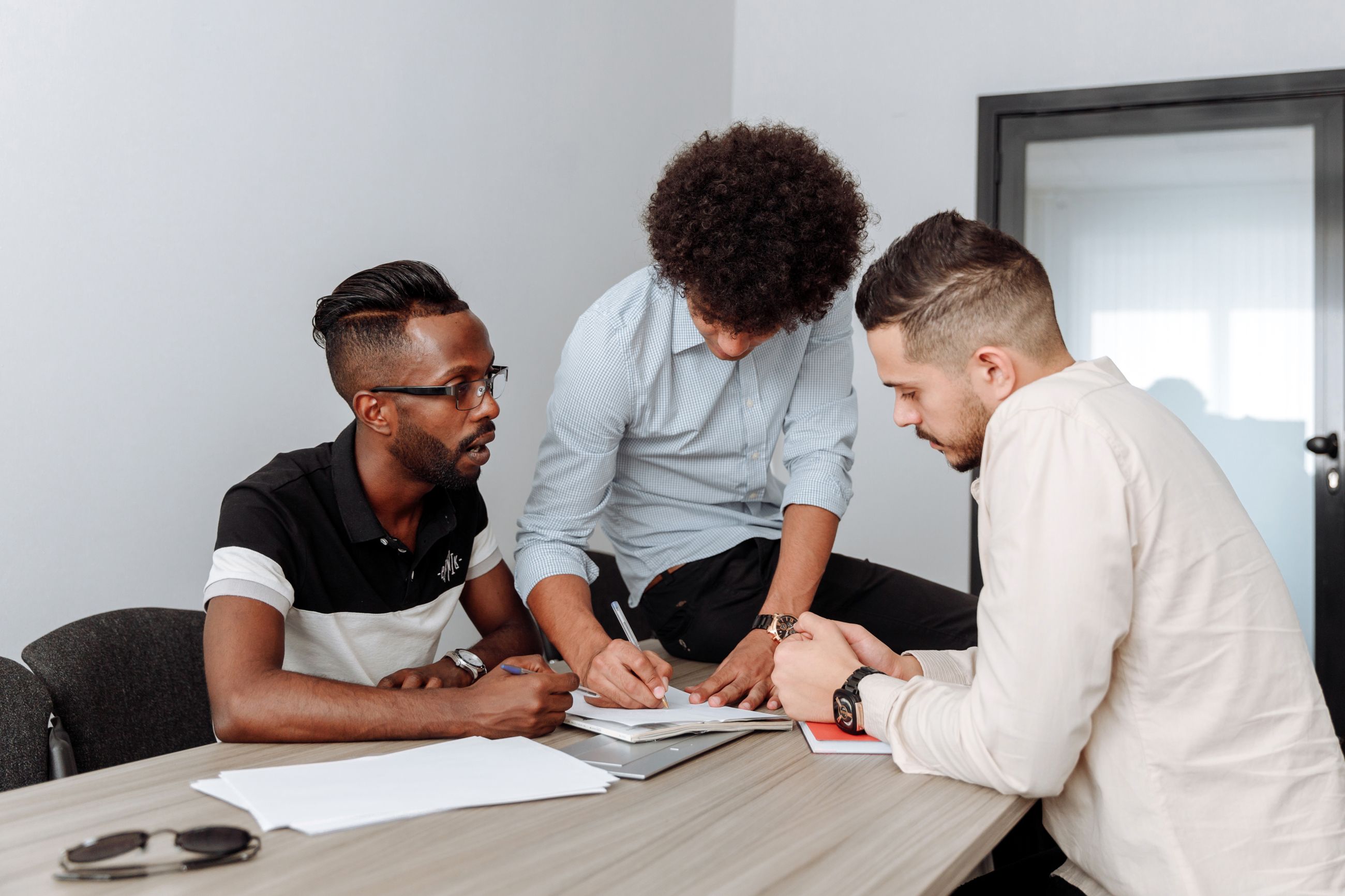 Trois professionnels examinent un dossier autour d'une table
